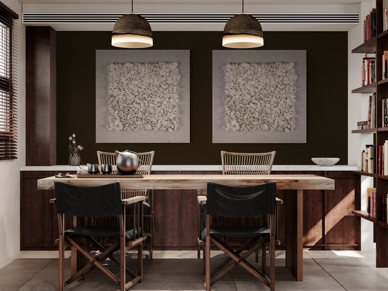 May include: A dining room with a wooden table and chairs. The table has a white marble top and a wooden base. There are two black chairs with wooden frames and a woven chair with a wooden frame. The walls are painted a dark brown color and there are two white framed pictures on the wall. There is a bookshelf on the right side of the image.