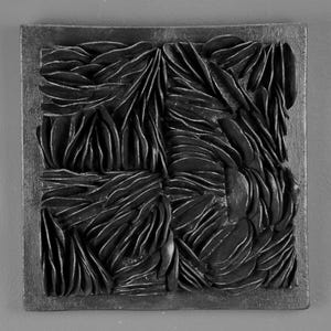 May include: Black and white abstract wall art sculpture with a textured surface. The sculpture is made of layered, overlapping shapes that create a sense of depth and movement.