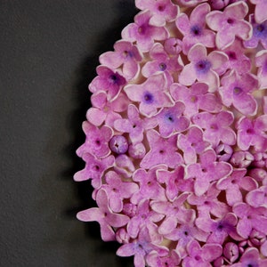 May include: A close-up of a cluster of small, light purple flowers. The flowers are arranged in a circular pattern and have a delicate, textured appearance.
