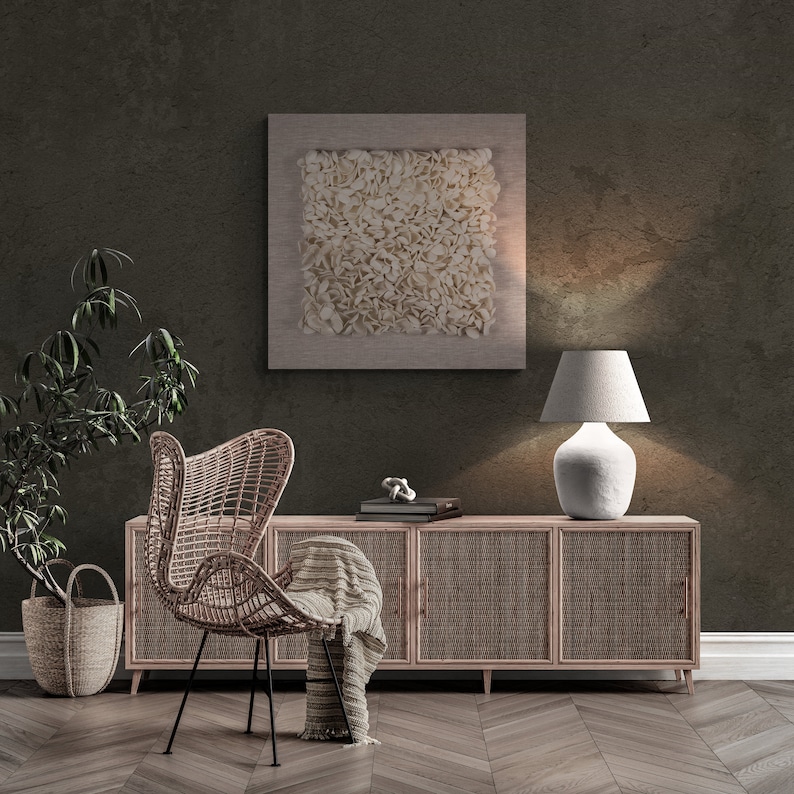 May include: A wicker chair with a throw blanket sits in front of a wooden cabinet with woven doors. A lamp with a white shade sits on the cabinet. A framed abstract art piece hangs on the wall behind the cabinet.