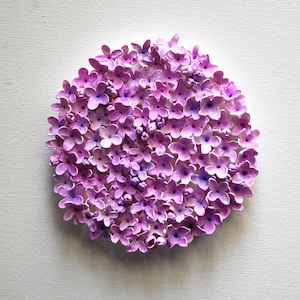 May include: A circular arrangement of small, purple flowers, resembling a cluster of lilacs, on a white background.