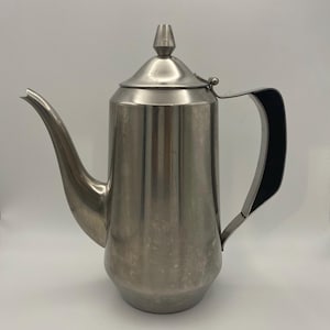 May include: A stainless steel coffee pot with a long spout and a black handle. The pot has a lid with a small, pointed knob. The pot is designed for brewing coffee and has a classic, vintage look.