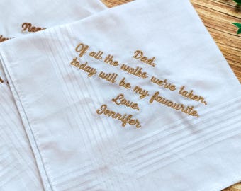 May include: Two white handkerchiefs with embroidered text in a cursive font. The text reads "Of all the walks we've taken, today will be my favourite. Love, Jennifer." The handkerchiefs have a subtle striped pattern.
