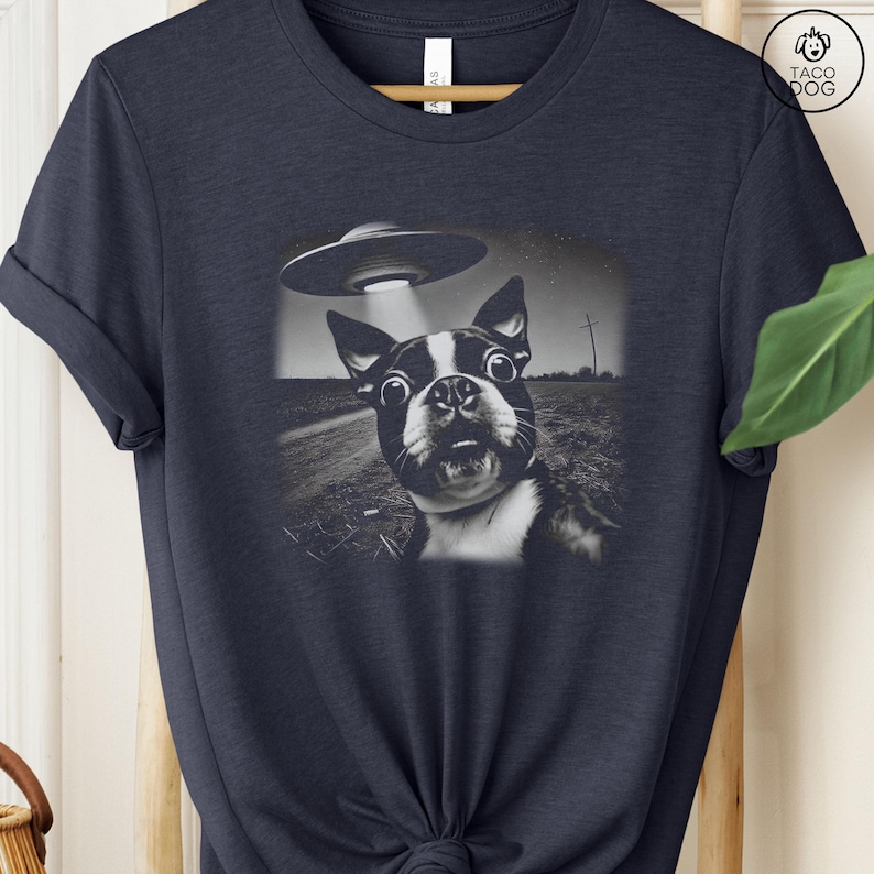 May include: A navy blue t-shirt with a black and white image of a Boston Terrier looking up at a UFO. The dog has a surprised expression on its face.