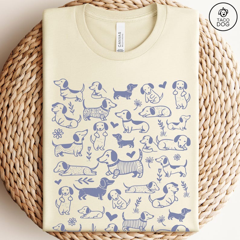May include: A light yellow t-shirt with a blue dachshund pattern. The shirt has the text "Taco Dog" in the top right corner.