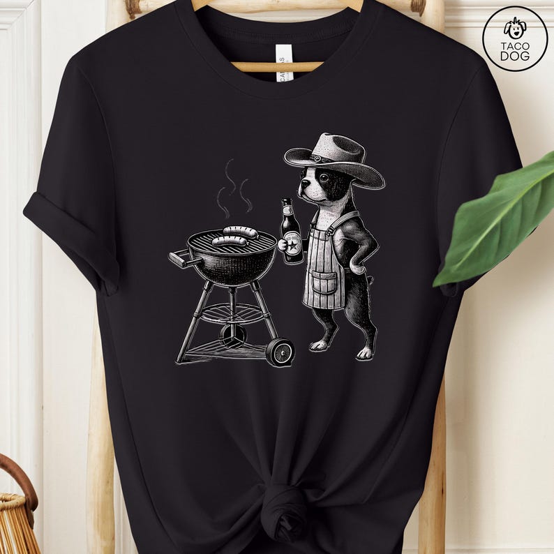 Peut inclure: Une illustration en noir et blanc d'un Boston Terrier portant un chapeau de cowboy et un tablier, faisant griller des saucisses sur un barbecue au charbon de bois. Le chien tient une bouteille de bi&egrave;re dans une patte.