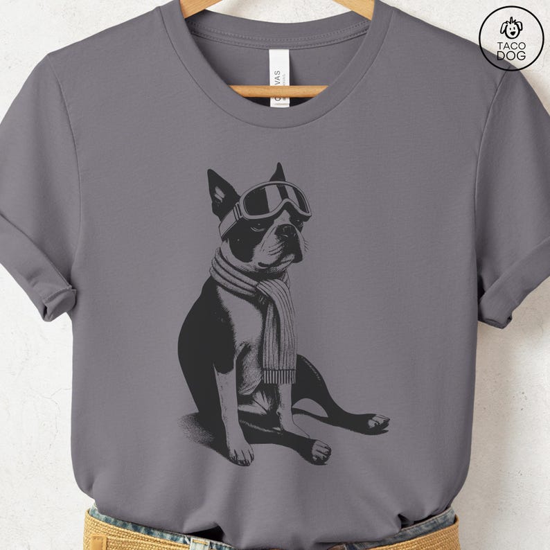 Puede incluir: Camiseta gris con una ilustraci&oacute;n en blanco y negro de un Boston Terrier con gafas de esqu&iacute; y una bufanda. El perro est&aacute; sentado. La camiseta tiene cuello redondo y mangas cortas.