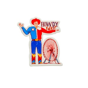 以下が含まれることがあります： 赤い、白、青のシャツを着た、漫画の牛仔のヴィンテージスタイルのステッカー。青いジーンズとカウボーイブーツを履いています。彼は腕を広げて「Howdy Folks!」と言っています。彼の後ろには赤い観覧車があります。
