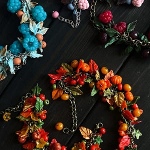 May include: A set of four bracelets featuring different themes: autumn leaves, pumpkins, blueberries, and raspberries. Each bracelet is made with polymer clay and features a chain link.