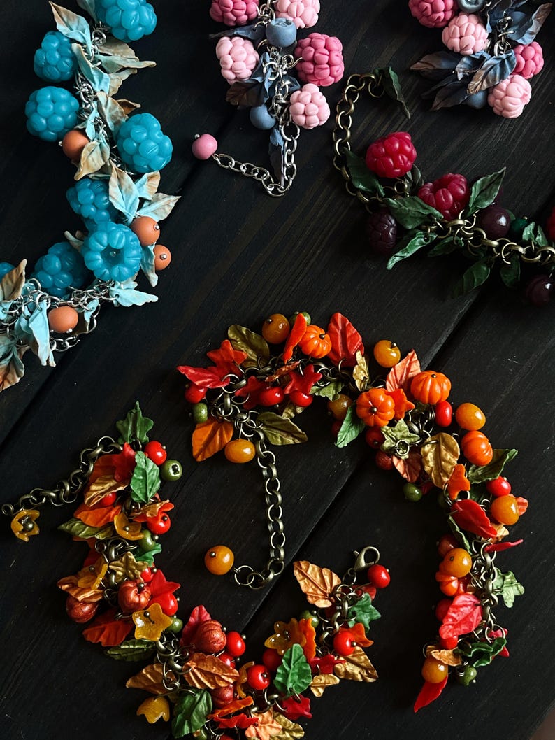 May include: A set of four bracelets featuring different themes: autumn leaves, pumpkins, blueberries, and raspberries. Each bracelet is made with polymer clay and features a chain link.