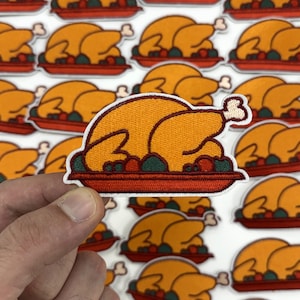 May include: Embroidered patch featuring a roasted turkey on a red platter with green and red accents. The turkey is golden brown with a white bone, and the patch has a stitched border. The background shows multiple identical patches.