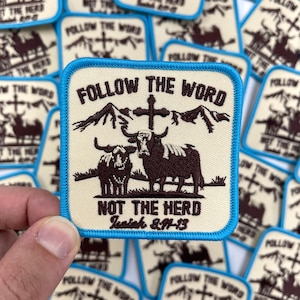 May include: A beige embroidered patch with a turquoise border. The patch features a cross, mountains, and two brown cows. The text on the patch reads "Follow the Word, Not the Herd, Isaiah 8:11-13".