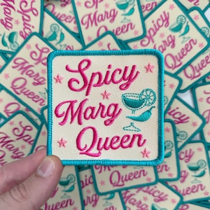 May include: A stack of white fabric patches with a turquoise border. The patches have pink embroidery that reads "Spicy Marg Queen" and a turquoise margarita glass with a lime wedge.