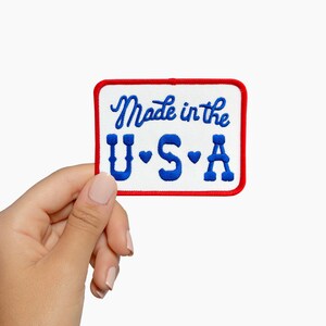 May include: Embroidered patch with the text "Made in the U.S.A." in blue script and block letters, with red border. The patch is rectangular with rounded corners.