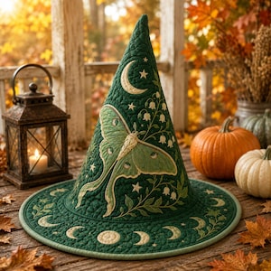 May include: A dark green quilted witch hat featuring an embroidered light green moth, lily of the valley flowers, stars, and a crescent moon. The wide brim is decorated with a repeating pattern of moon phases in a light cream color.