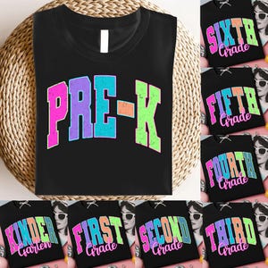 Puede incluir: Camisetas negras con texto colorido. Una camiseta dice "PRE-K" en una fuente retro. Otras camisetas muestran "Kindergarten", "First Grade", "Second Grade", "Third Grade", "Fourth Grade", "Fifth Grade" y "Sixth Grade".