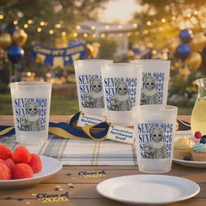 K&ouml;nnte beinhalten: Mattierte Plastikbecher mit dem Text "SENIOR 2026" und einem Foto eines Kindes mit Sonnenbrille. Die Becher sind auf einem Holztisch mit einem Teller Erdbeeren, Cupcakes und Abschlussdekorationen angeordnet.