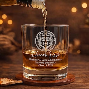 May include: A clear glass tumbler with the Harvard University seal and the name "Eleanor Rose" etched on it. The glass is filled with amber liquid, and more is being poured from a bottle. Text below reads "Bachelor of Arts in Economics, Harvard University, Class of 2026."