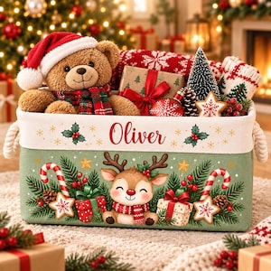 Könnte beinhalten: Ein rechteckiger grüner Stoff-Aufbewahrungskorb mit dem Namen Oliver in roter Schrift, verziert mit einem Rentier, Zuckerstangen, Geschenken und Stechpalmen. Der Korb ist gefüllt mit einem Teddybären mit Weihnachtsmütze, Geschenken und Tannen.