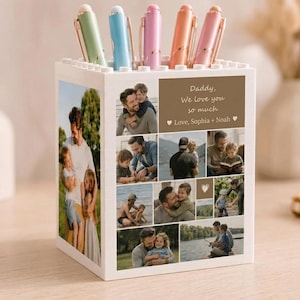 Puede incluir: Un portalápices blanco con un collage de fotos familiares. El soporte tiene una sección superior con bolígrafos de colores. El texto en el soporte dice "Daddy, We love you so much" y "Love, Sophia + Noah".