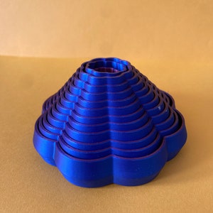 May include: A set of 10 blue flower-shaped cookie cutters stacked in a cone shape. The cutters are made of plastic and have a smooth, glossy finish.