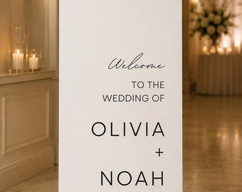 May include: A tall, white, arched wedding welcome sign featuring black text that reads: Welcome TO THE WEDDING OF OLIVIA + NOAH 07.06.2025. The sign has a smooth, flat surface and a rounded top edge, standing upright as a decorative display piece.