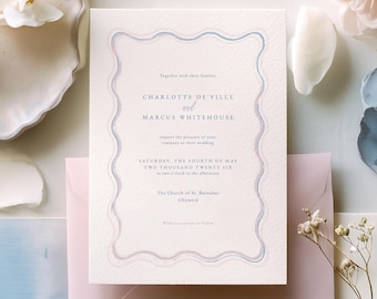 May include: Wedding invitation with a wavy blue and pink border, featuring the names Charlotte de Ville and Marcus Whitehouse. The invitation is on textured paper, surrounded by flowers, a pink envelope, and decorative elements.