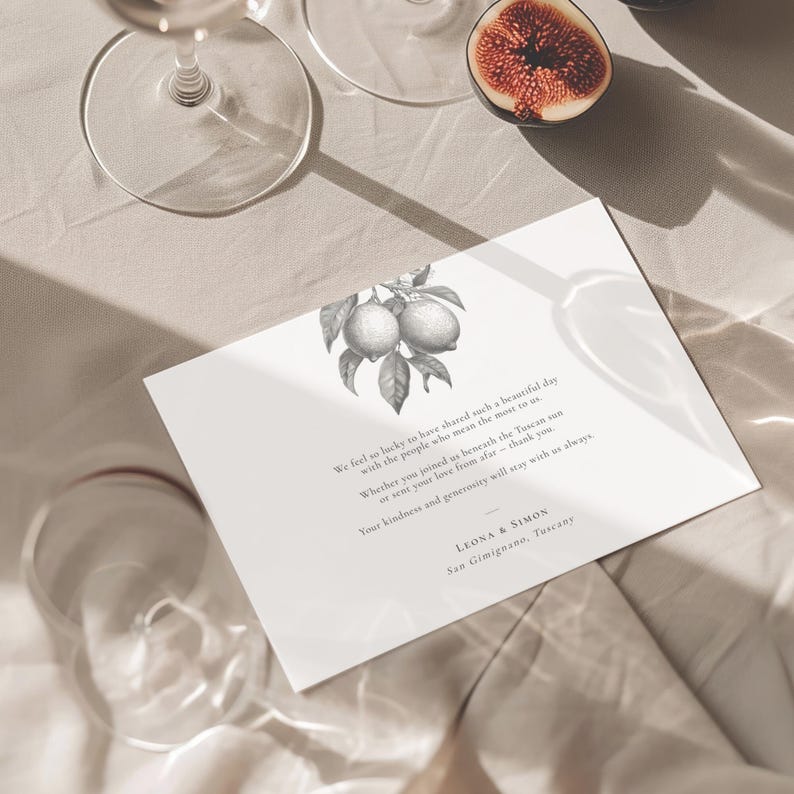 Great and white citrus botanical thank you note for a wedding displayed on linen fabric with a fig to the side and glasses.