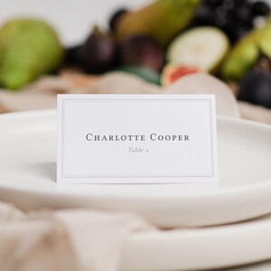 Elegant bordered folded wedding place card editable template with guest name and table number.