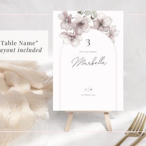 Sakura blossom blush pink wedding table name sign displayed on a stand