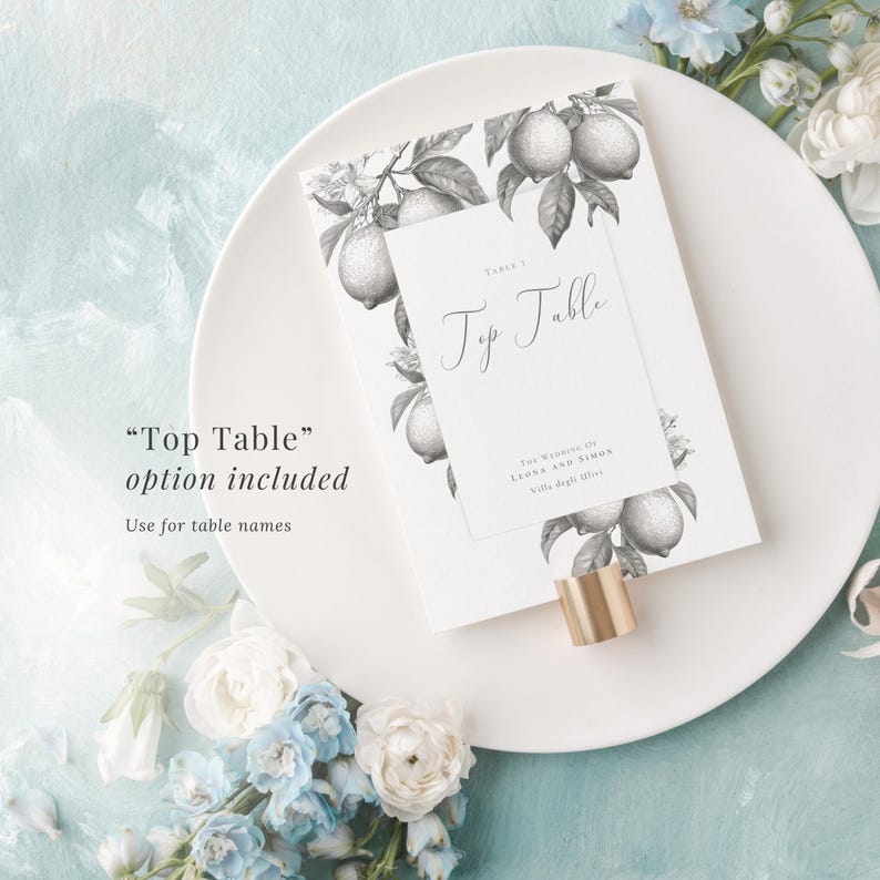 Elegant top table sign included with monochrome lemon design. Use for table names. Shown in a holder laid on a plate, with a blue painted background and blue and white flowers