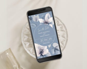 May include: A blue and white floral save the date card on a smartphone screen. The text reads "Save the Date" with the names "Joanne Makepiece and Simeon Barker" and the date "21 04 26" with the location "Jonestown".