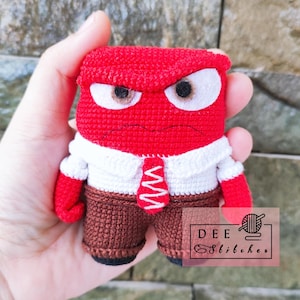 Può includere: Un giocattolo di peluche all'uncinetto del personaggio Rabbia del film Inside Out. Il giocattolo è rosso con una camicia bianca, pantaloni marroni e una cravatta rossa. Il giocattolo ha le sopracciglia aggrottate, occhi arrabbiati e una smorfia.