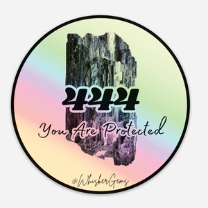 May include: A round sticker with a rainbow gradient background. The sticker features a black and white image of a crystal with the number "444" and the text "You Are Protected" in black. The text "@WhiskerGems" is at the bottom of the sticker.