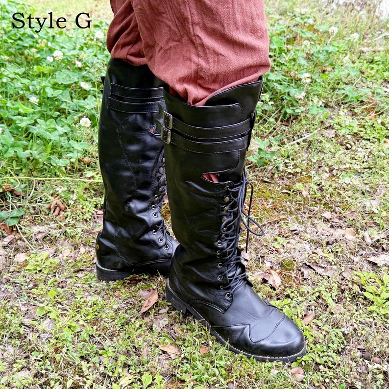 May include: Black leather knee-high boots with laces and buckles. The boots have a rounded toe and are worn with reddish-brown trousers. The text "Style G" is in the upper left corner.