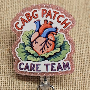 May include: A pink glitter badge reel with the words "CABG PATCH CARE TEAM" in red and purple. The badge features a detailed illustration of a human heart in red and blue, surrounded by green leaves.