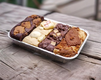 Może przedstawiać: Prostokątna taca wypełniona różnymi wypiekami, w tym brownie i blondie. Smakołyki ułożone są w sekcjach, prezentując różne smaki i dodatki, takie jak kawałki czekolady i ciasteczka. Taca stoi na rustykalnej drewnianej powierzchni.