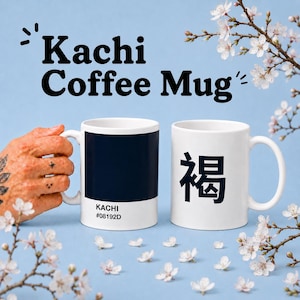 Könnte beinhalten: Zwei weiße Keramik-Kaffeetassen. Eine Tasse hat einen marineblauen Block mit dem Text "KACHI #08192D". Die andere Tasse hat ein schwarzes japanisches Zeichen. Die Worte "Kachi Coffee Mug" stehen über den Tassen.