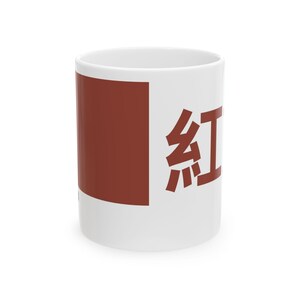 May include: White ceramic mug featuring a large maroon rectangle and the Japanese character for "red" in maroon. The mug is cylindrical and has a standard handle.
