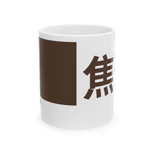 May include: White ceramic mug with a brown square and Japanese characters. The mug has a glossy finish and a simple design, suitable for coffee, tea, or other beverages. The Japanese characters are in a dark brown color.