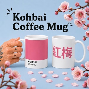 May include: Two white coffee mugs with the text "Kohbai Coffee Mug". One mug has a pink color block with the text "KOHBAI #E16B8C". The other mug has Japanese characters. Pink cherry blossoms are in the background.