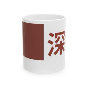 May include: White ceramic mug with a maroon square and maroon Japanese characters. The mug is cylindrical and has a handle. The design is on the side of the mug.