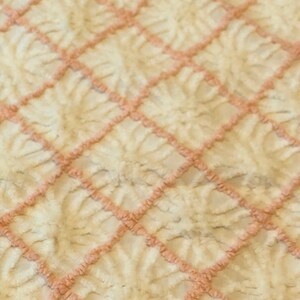 May include: A white and pink plush throw blanket with a diamond pattern. The blanket is soft and fluffy.