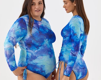 Op de afbeelding: Twee vrouwen dragen langarmige, blauwe en witte mesh-bodysuits met een trekkoord aan de zijkant.
