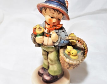 Vintage Collectible Hummel Goebel Figurine Called "Easter Greetings". The Little Boy Carries a Bouquet of Flowers and Basket of Baby Chicks.