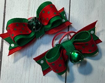 May include: Two red and green Christmas-themed hair bows with white polka dots and jingle bells.