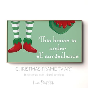 Könnte beinhalten: Gerahmter digitaler Kunstdruck zum Thema Weihnachten mit hellgrünem Hintergrund. Das Kunstwerk zeigt Elfenbeine mit roten Schuhen und dem Text "This house is under elf surveillance". Der Rahmen ist goldfarben.