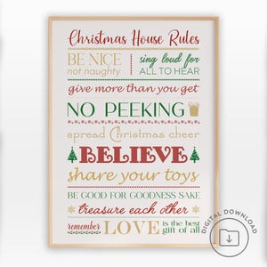 May include: A framed print featuring "Christmas House Rules" in red and gold lettering. The rules include "Be Nice," "Believe," and "Love is the best gift of all." The print has a light beige background and a wooden frame.