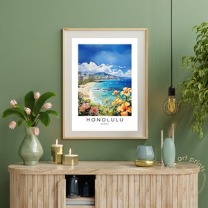 May include: A framed print of a colorful painting depicting a beach scene in Honolulu, Hawaii. The painting features a beach with blue water, white sand, and palm trees. The city skyline is visible in the background. The print is framed in a light wood frame.