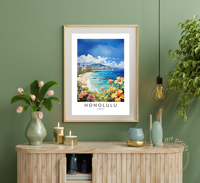 May include: A framed print of a colorful painting depicting a beach scene in Honolulu, Hawaii. The painting features a beach with blue water, white sand, and palm trees. The city skyline is visible in the background. The print is framed in a light wood frame.
